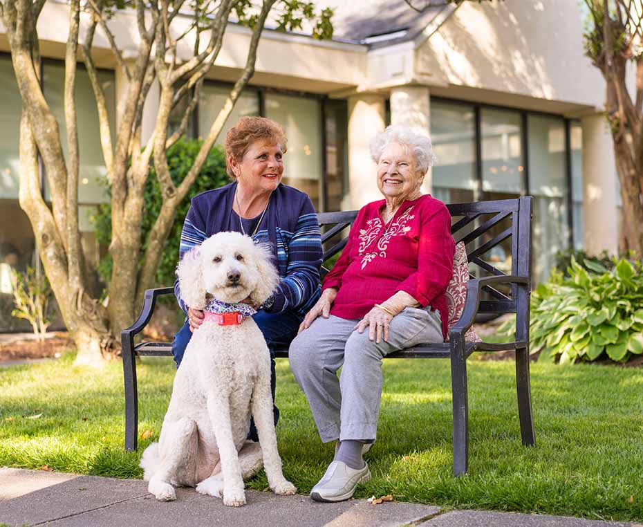 two happy senior women with a white dog